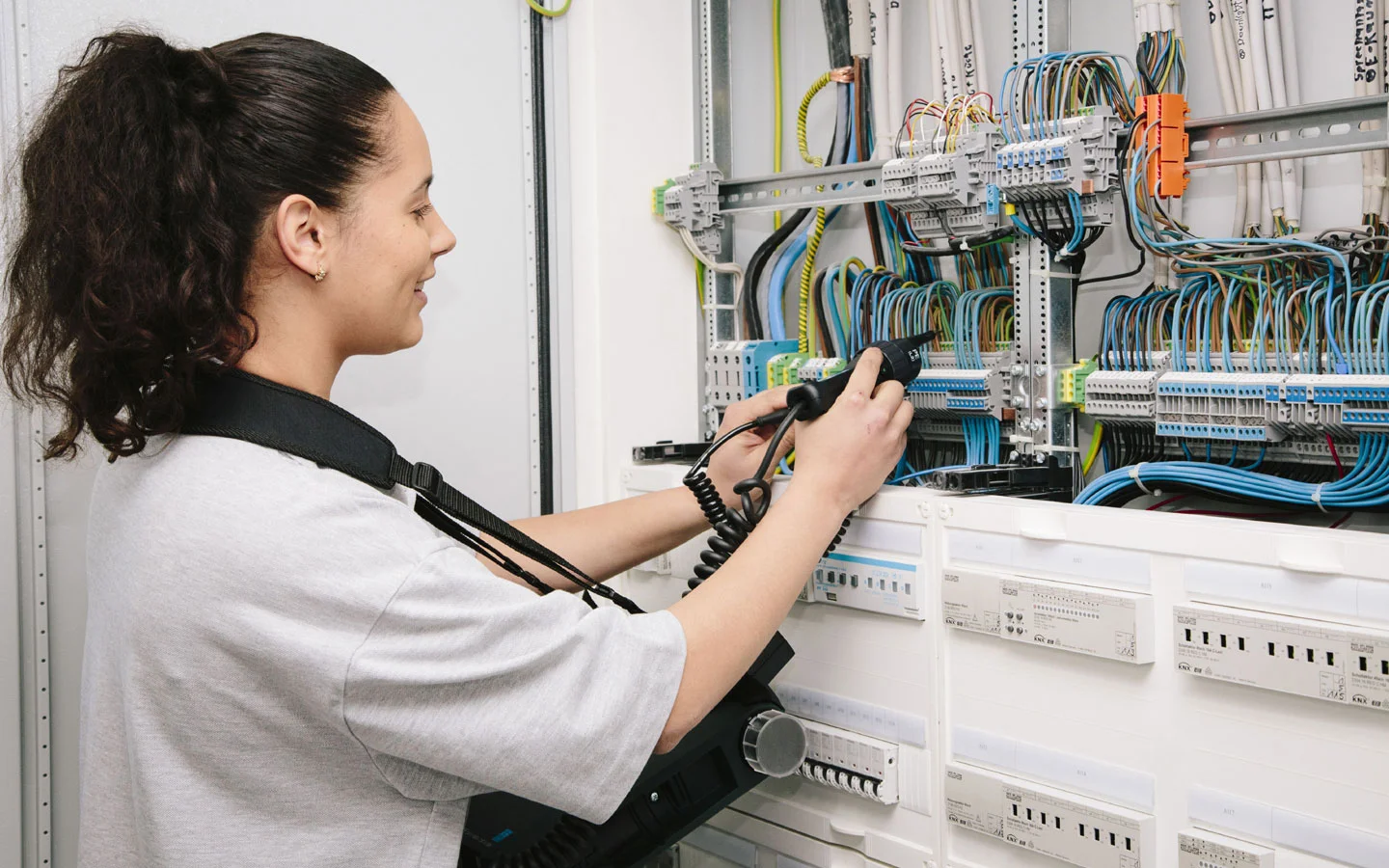 E-CHECK - Mitarbeiterin prüft im Schaltschrank mit einem Meßgerät &middot; Elektro Busch GmbH