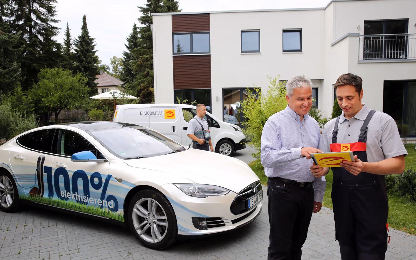 E-Mobilität - Mitarbeiter mit Kunden vor Elektrofahrzeugen 100% elektrisch &middot; Elektro Busch GmbH