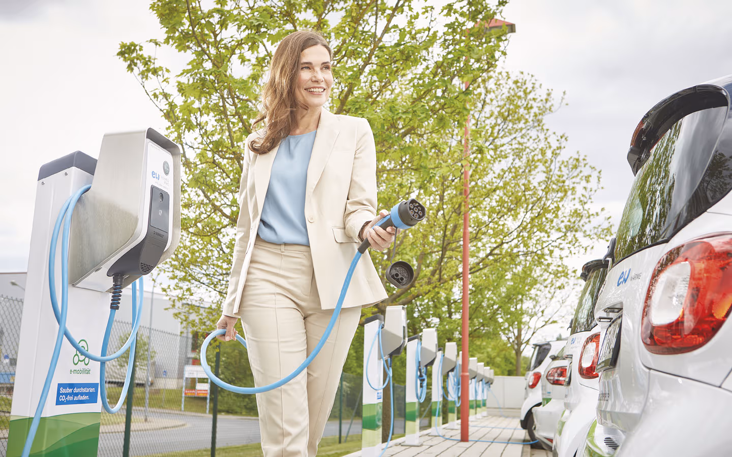 E-Mobilität - Kundin vor Ladestation mit Stecker in der Hand &middot; Elektro Busch GmbH